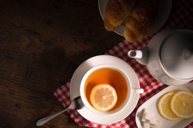 Imagen de la vista superior de una taza de té con limón en la mesa de madera