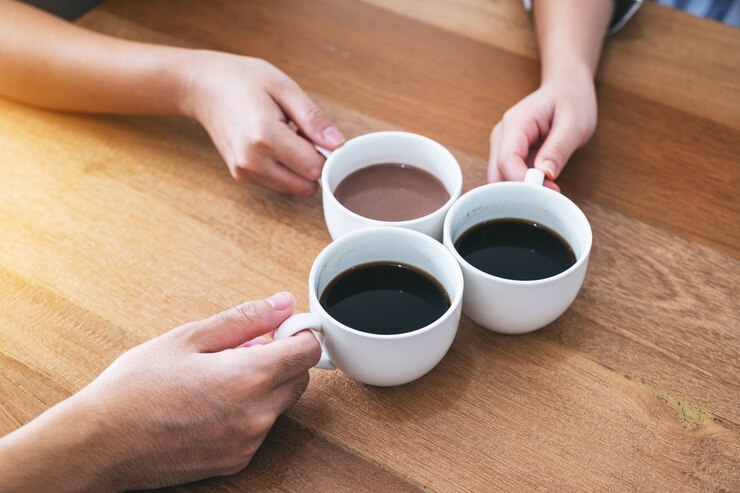 Imagen de la vista superior de tres personas que tintinean las tazas de café en la mesa de madera en el café