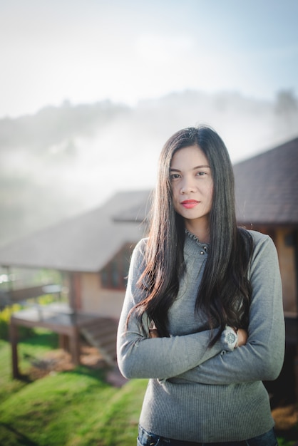 Imágenes de hermosas mujeres asiáticas de pie en hermosas atracciones naturales Mujer asiática con el pelo largo en un clima frío y brumoso.