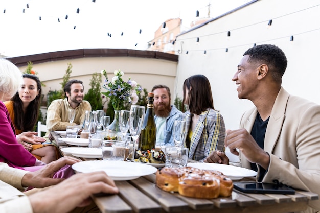 Imágenes de la narración de un grupo multiétnico de personas cenando en una azotea. Familiares y amigos hacen un reencuentro en casa