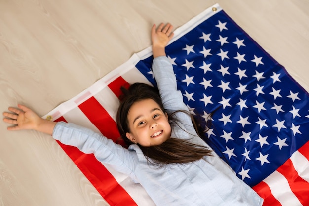 Foto imágenes de una niña encantadora sobre el fondo de la bandera de estados unidos.