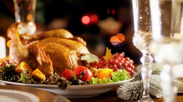 Imágenes de panorámica 4k de primer plano de pavo al horno con verduras y vasos llenos de vino champán espumoso. Mesa de comedor servida para familia numerosa en fiestas de invierno y celebraciones.