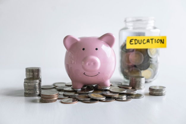 Foto imágenes de pila de monedas apiladas y hucha sonriente rosa para crecer y ahorrar con caja de dinero, ahorrar dinero para el plan futuro y el concepto de fondo educativo.