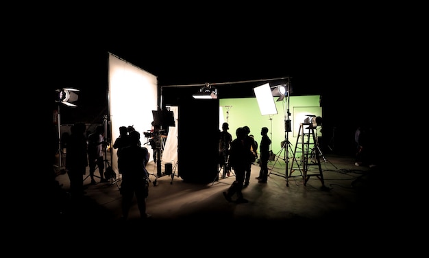 Foto imágenes de silueta de producción de video detrás de escena o b-roll o realización de película comercial de televisión que el equipo de filmación del equipo de iluminación y el camarógrafo trabajan junto con el director en el estudio con equipo
