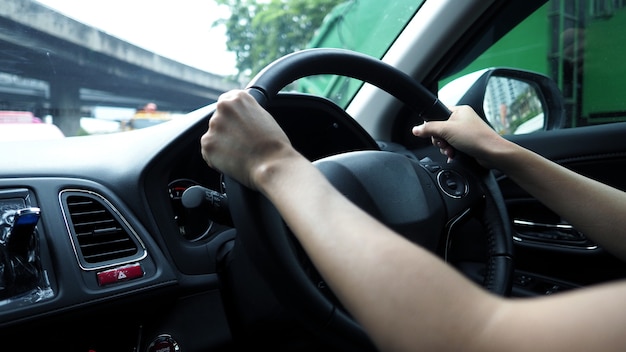 Imagens aproximadas de mãos de mulheres dirigindo e controlando o carro com confiança e segurança em qual carro
