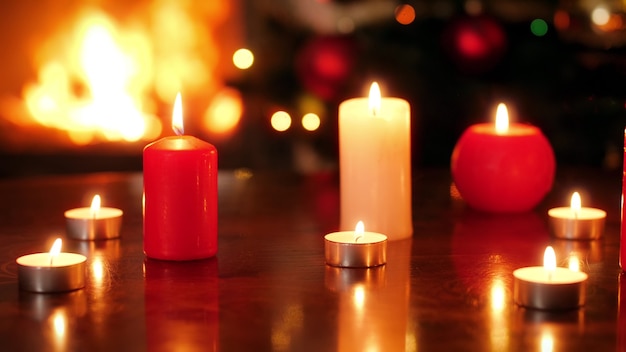 Imagens de closeup 4k de queima de velas contra o fogo na lareira e a árvore de natal brilhante. plano de fundo ou cenário perfeito para o natal ou ano novo