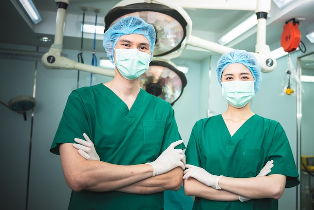 Imagens de retrato Uma equipe de médicos asiáticos cirurgiões masculinos e femininos em pé na sala de cirurgia