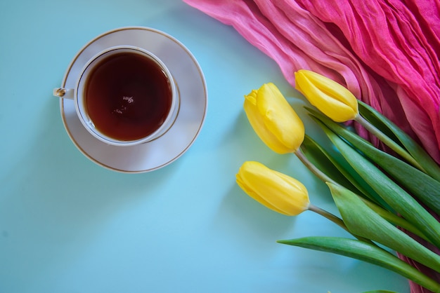 Imagens românticas com tulipas amarelas e xícara de chá em fundo azul