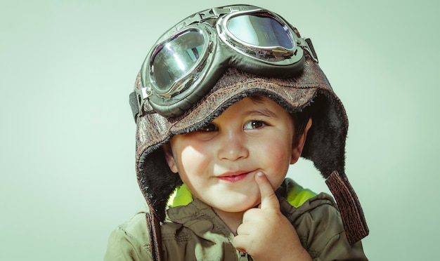 Imaginación, niño pequeño y lindo, jugando en casa con guerras y paz, niño divertido vestido con sombrero militar y gafas