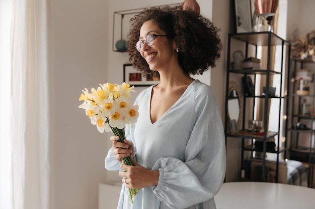 Imagine uma jovem bonita negra com flores em casa