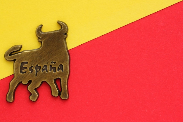 Imán de nevera de recuerdo de metal de toro con la palabra España en español sobre fondo rojo y amarillo. Viajar