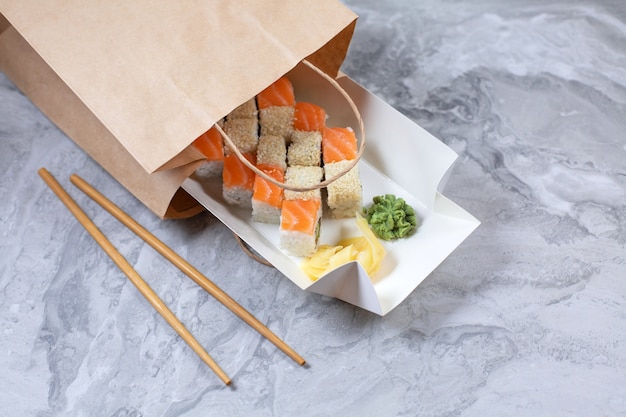 Imbissbox mit Sushi-Rollen in brauner Papiertüte.