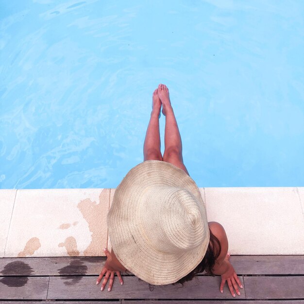 Foto imediatamente acima da foto da mulher usando chapéu sentada à beira da piscina