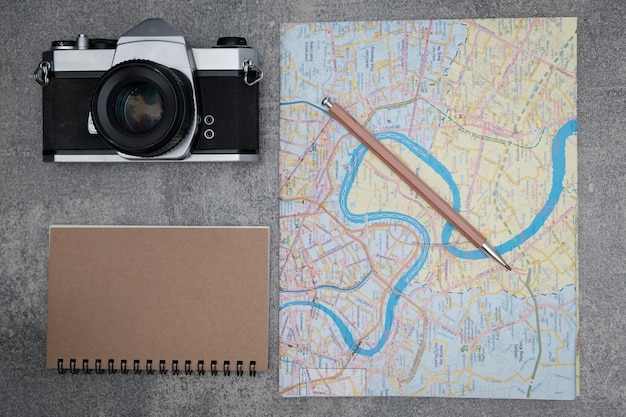 Foto imediatamente acima do tiro do mapa com caderno em espiral e câmera em uma mesa de concreto