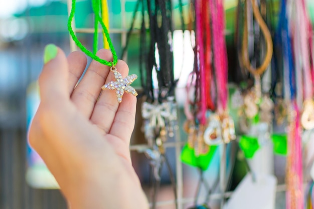 Imitationsschmuck für Frauen Perlenketten auf der Vitrine des Straßenhandels Die Hand einer Frau wählt Perlen aus