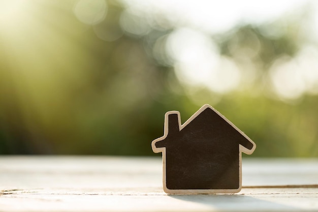 Immobilienkonzept Häuschen mit Platz für Text auf dem Holztisch im Garten