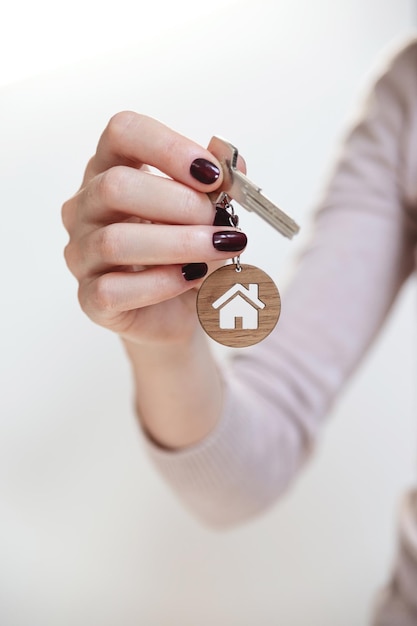 Immobilienkonzeptschlüssel mit einem hausförmigen Schlüsselbund in der Hand einer Frau