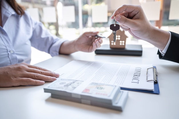 Immobilienmakler präsentieren Wohnungsbaudarlehen und senden dem Kunden nach Vertragsunterzeichnung Schlüssel