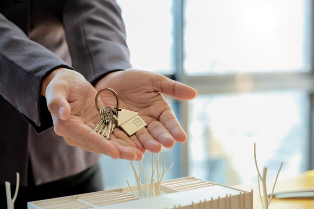 Immobilienmakler übergibt Hausschlüssel mit genehmigtem Hypothekenantragsformular und bietet Handschlag an