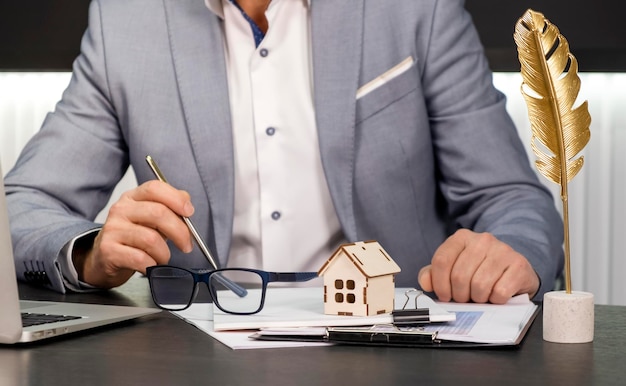 Immobilienmanager im Immobilienmaklerbüro hinter Hausmodellinvestitions-Darlehensvertrag Hauskauf- und -verkaufskonzept