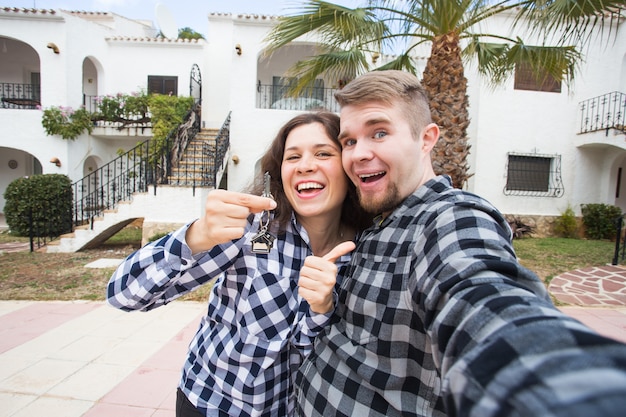 Imobiliário de propriedade e conceito de apartamento feliz casal jovem engraçado mostrando as chaves de seus