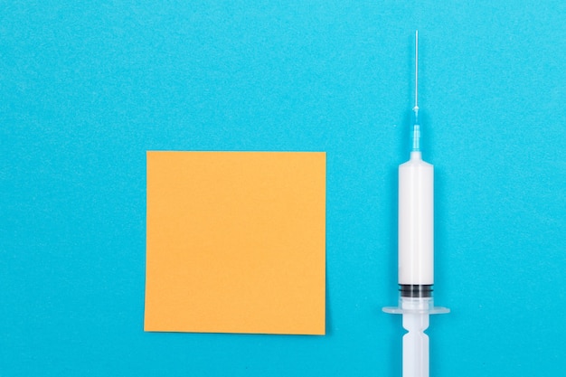 Impf- oder Wiederholungsimpfungskonzept eine medizinische Spritze auf blauem Tisch