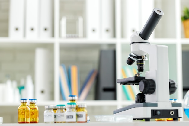 Impffläschchenflaschen und Mikroskop auf dem Tisch in einem wissenschaftlichen Labor