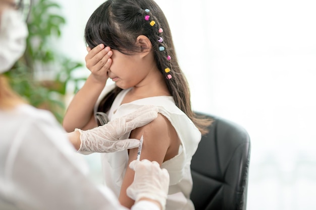 Impfkonzept Ärztin impft süßes kleines Mädchen in der Klinik