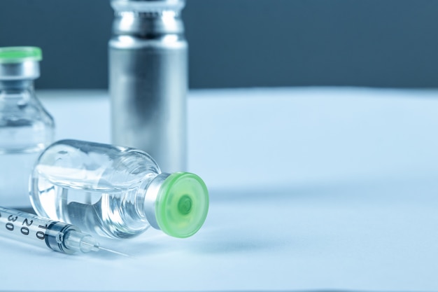 Impfstoff in Fläschchen und Spritzen-Nahaufnahme auf einer weißen grauen Oberfläche des Tisches, medizinisches Konzept, Labor, subkutane Injektionsimpfung, Dosis. Immunisierung gegen Krankheitsbehandlung.