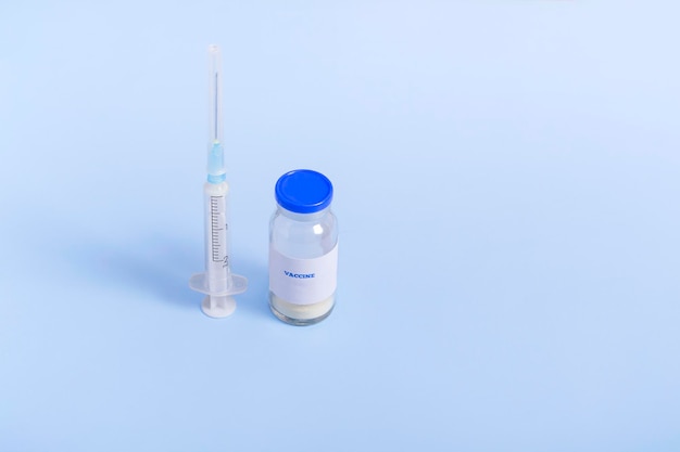 Impfstoff zur Immunisierung gegen COVID und eine Spritze auf farbigem Hintergrund. Medizinisches Konzept hautnah