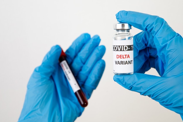 Impfstoffflaschen Covid - 19 Delta-Variante, Fläschchen Medizin und Spritzeninjektion einzeln auf Weiß. Coronavirus DELTA 2019-ncov. Impfstoffflaschen an der Frauenhand