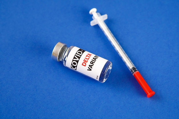 Impfstoffflaschen Covid - 19 Delta-Variante, Fläschchen Medizin und Spritzeninjektion isoliert auf Blau. Coronavirus DELTA 2019-ncov.