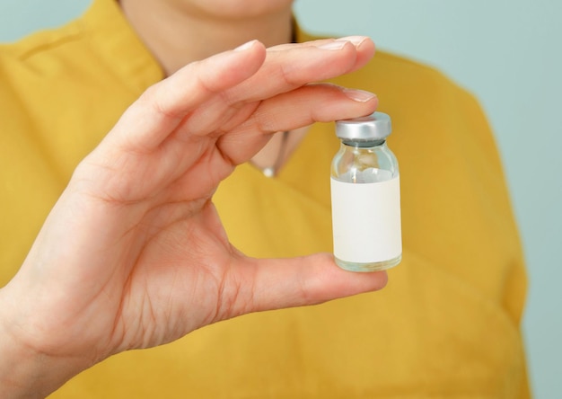 Impfstoffglasflasche zur Impfung gegen Influenza und Coronavirus in der Hand der Frau