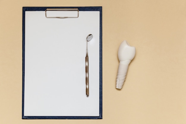 Foto implante dentário e pasta com clipe para folhas de papel a4 em fundo bege