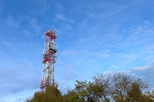 Una imponente estructura de comunicación roja y blanca La rejilla metálica de la torre está adornada con varias antenas y equipos esenciales para la transmisión de señales Es un símbolo del ingenio humano