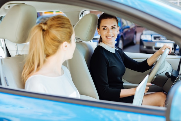 Importancia de la seguridad. Alegre mujer encantadora positiva conduciendo un automóvil y usando un cinturón de seguridad mientras piensa en su seguridad