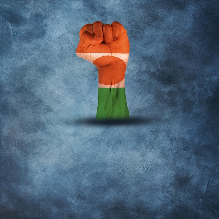Foto impresión de la bandera de níger con mano de perforación en un fondo de texturas azules con copia de espacio
