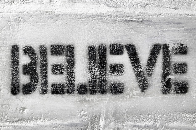 Impresión de la plantilla negra con textura de la palabra creer en la pared de ladrillo blanco desgastado