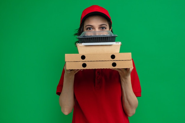 Foto impresionada joven bonita entrega mujer sosteniendo contenedores de comida y cajas de pizza