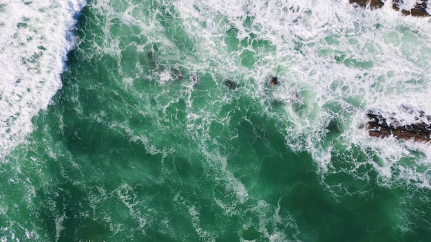 Impresionante agua de mar espumosa salpicando piedras de la orilla del mar ondas azules tormentosas aéreas