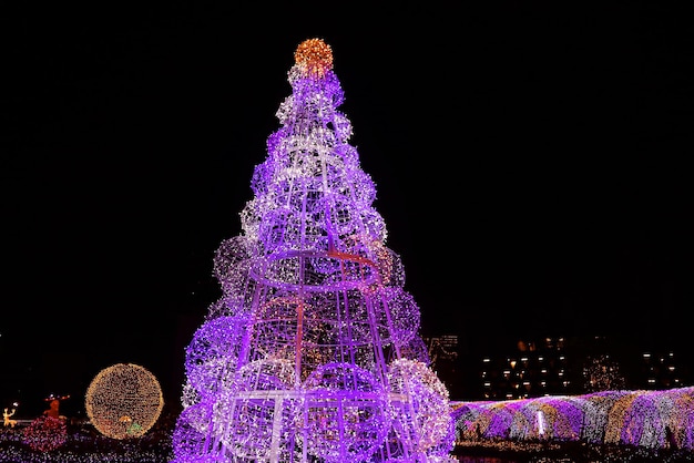 Impresionante árbol de Navidad gigante púrpura y dorado brillando contra el cielo nocturno