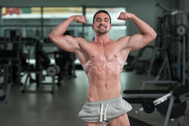 Impresionante culturista mostrando sus músculos y posando en el gimnasio