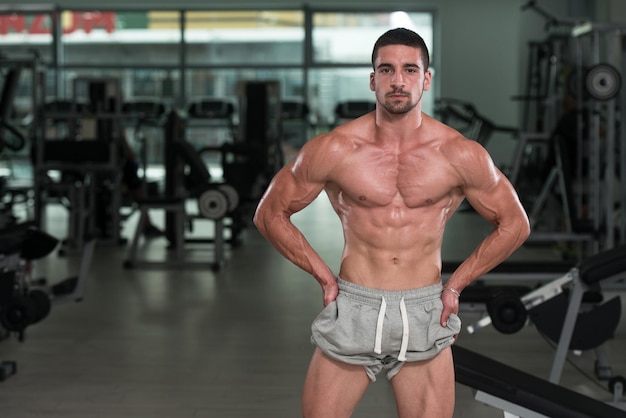 Impresionante culturista mostrando sus músculos y posando en el gimnasio