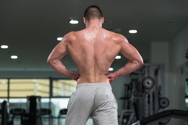 Impresionante culturista mostrando sus músculos y posando en el gimnasio