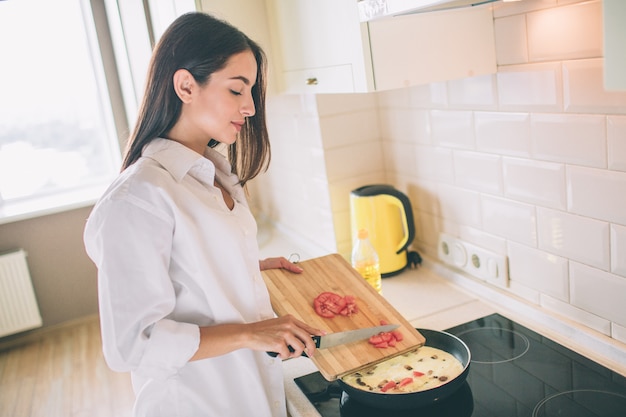 Impresionante joven está cocinando el desayuno en la cocina.