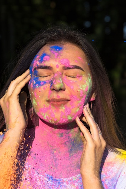 Impresionante mujer morena posando con explosión de polvo Gulal azul y amarillo en el parque