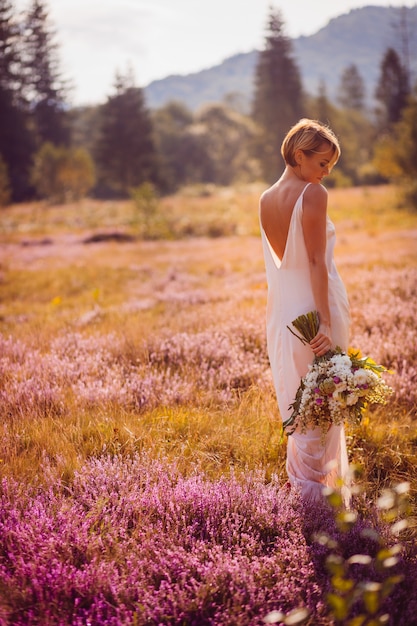 impresionante novia cruzando el campo de flores violetas