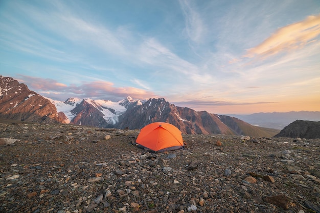 Impresionante paisaje con carpa naranja vívida con vista a altas montañas nevadas en colores del amanecer Paisaje colorido con rocas doradas iluminadas por el sol y montañas al amanecer Oro temprano en la mañana a gran altura