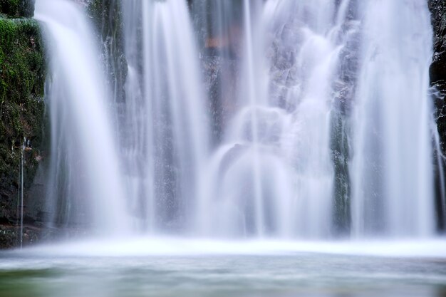Impresionante paisaje de hermosa cascada en el río de montaña con agua espumosa blanca cayendo desde un acantilado rocoso en la selva tropical de verano.