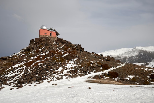 Un impresionante paisaje invernal cubierto de nieve de la cordillera de Sierra Nevada con un observatorio distante visible contra un cielo helado